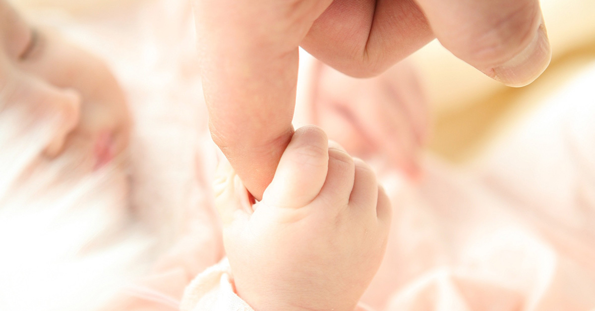 Baby hält den Finger eines Erwachsenen fest